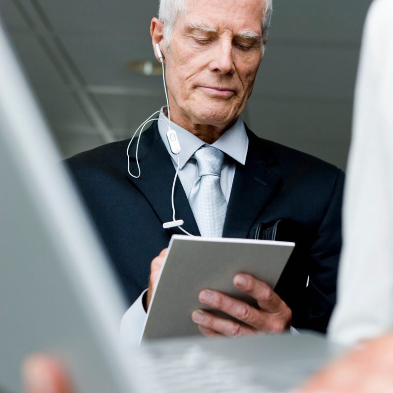 Older man with head phones taking notes